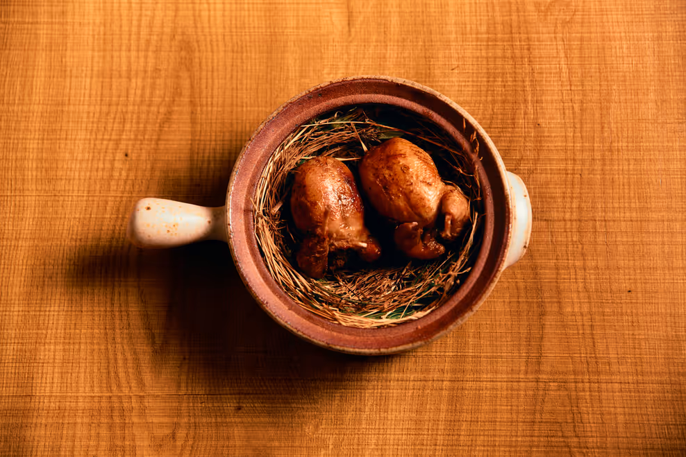 Quail stuffed with pork, chestnut and shiitake, served in a clay pot on a nest of straw
